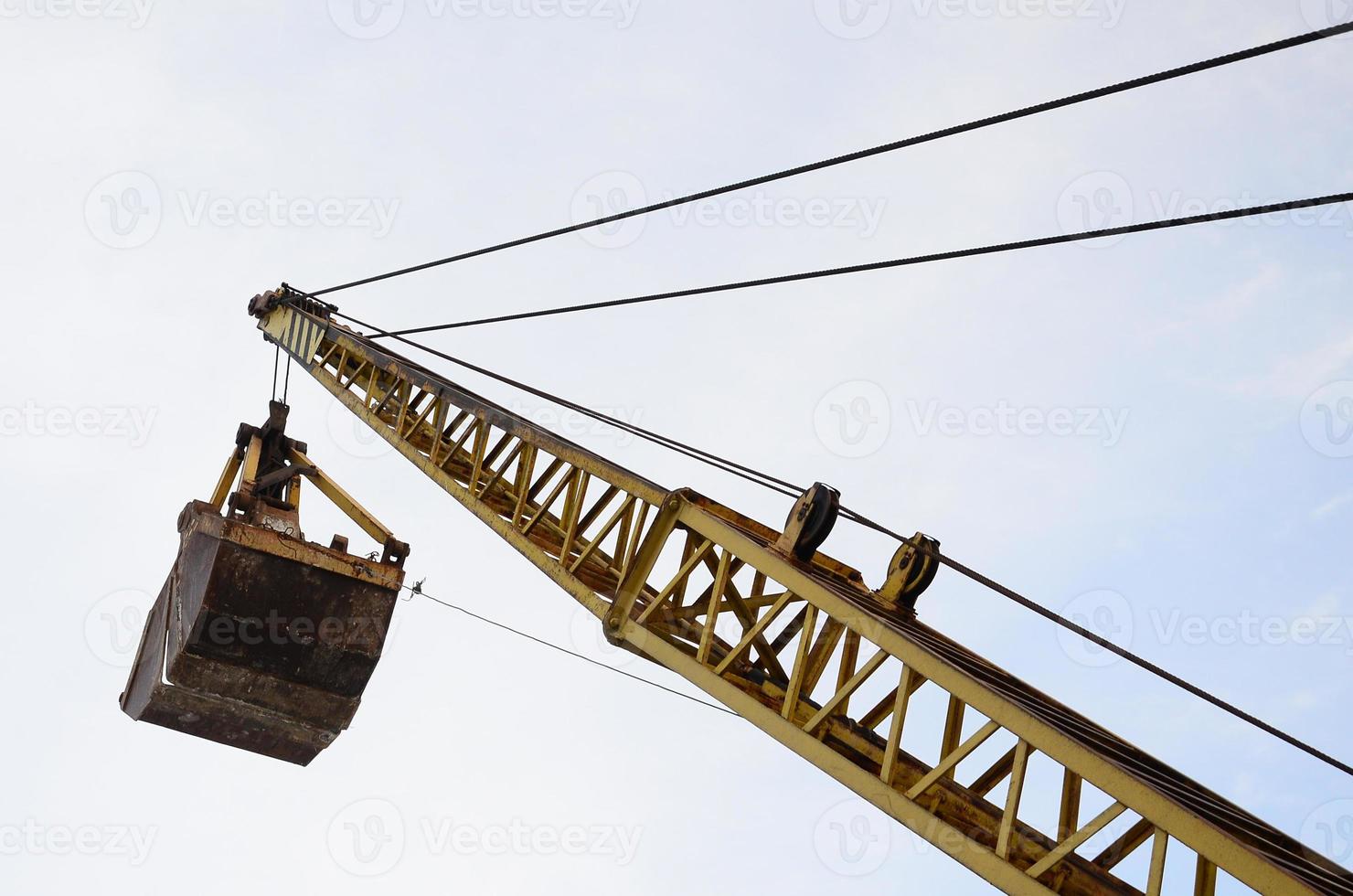 Old yellow mechanical clamshell grab on blue sky background photo