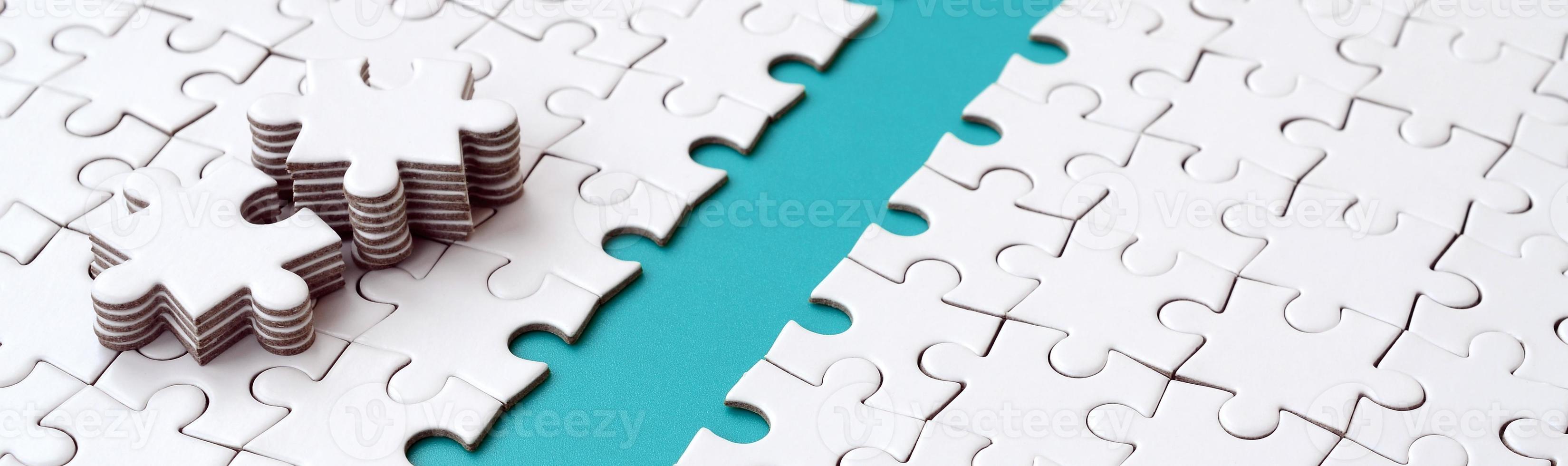 The blue path is laid on the platform of a white folded jigsaw puzzle. The missing elements of the puzzle are stacked nearby. Texture image with space for text photo