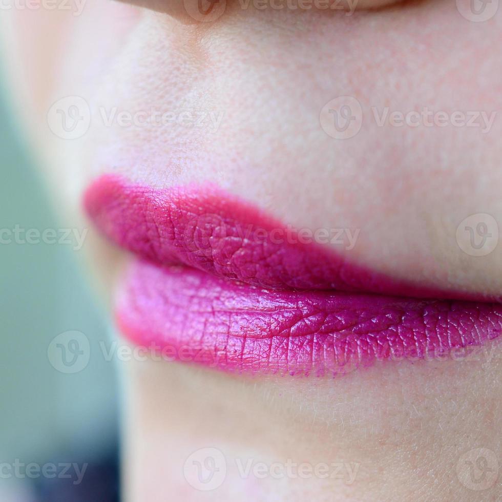 Close up shot of woman lips with glossy fuchsia lipstick photo