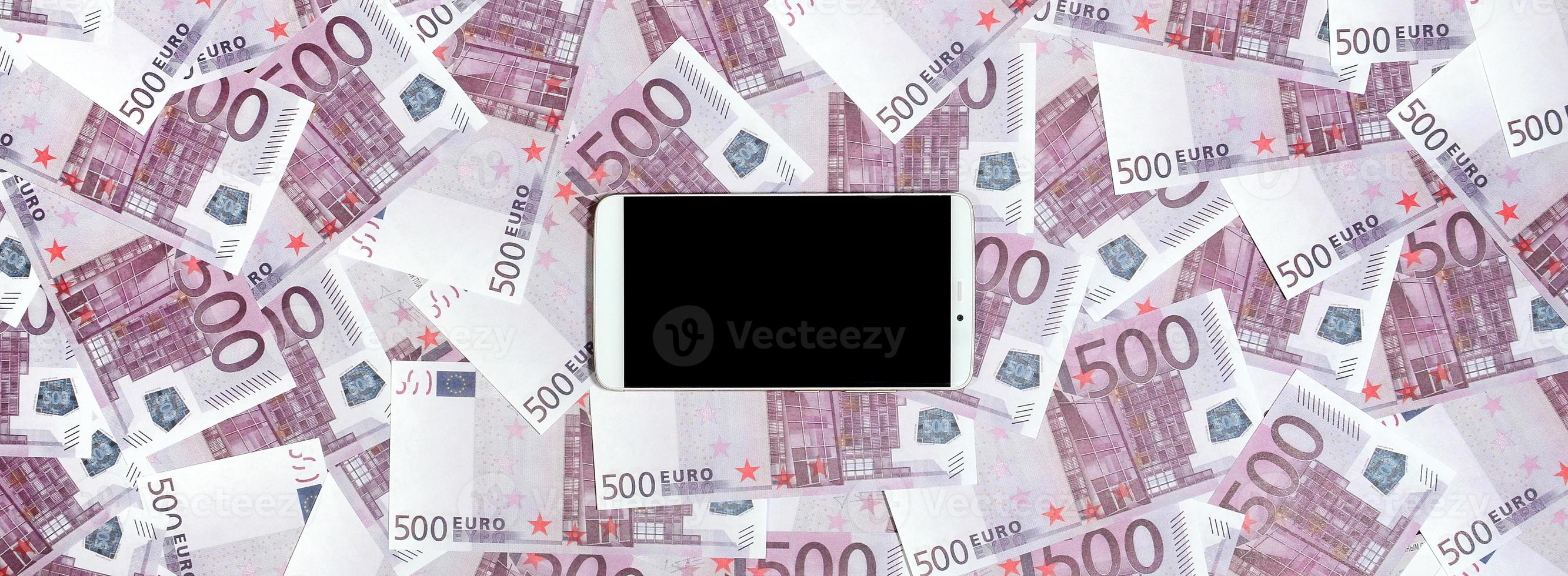 Purple 500 euro money bills and a smartphone with black screen. Copy space. The concept of online banking, money management and shopping with modern technology photo