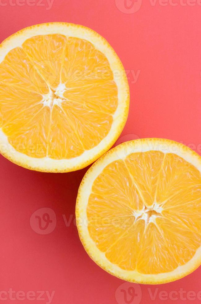 Top view of a several orange fruit slices on bright background in red color. A saturated citrus texture image photo