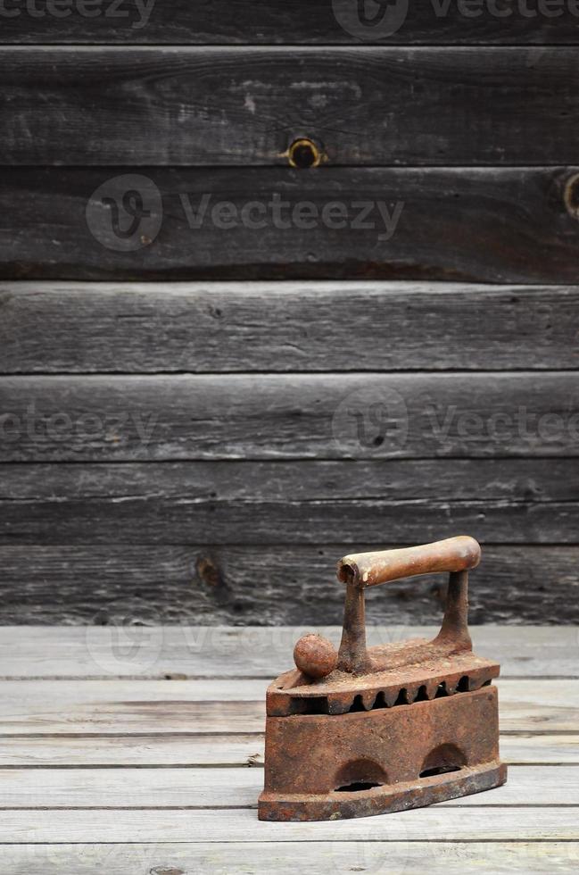 The heavy and rusty old coal iron lies on a wooden surface photo