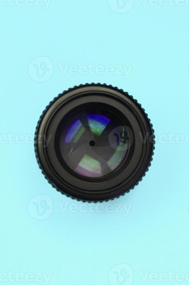 Camera lens with a closed aperture lie on texture background of fashion pastel blue color paper photo