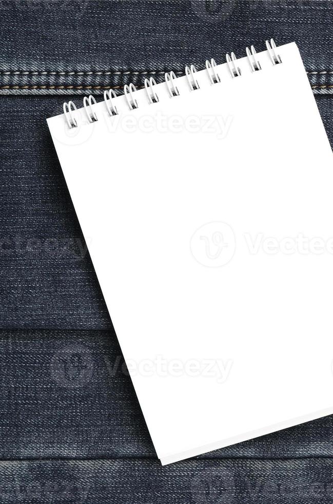 cuaderno blanco con páginas limpias sobre fondo de jeans azul oscuro. imagen con espacio de copia foto