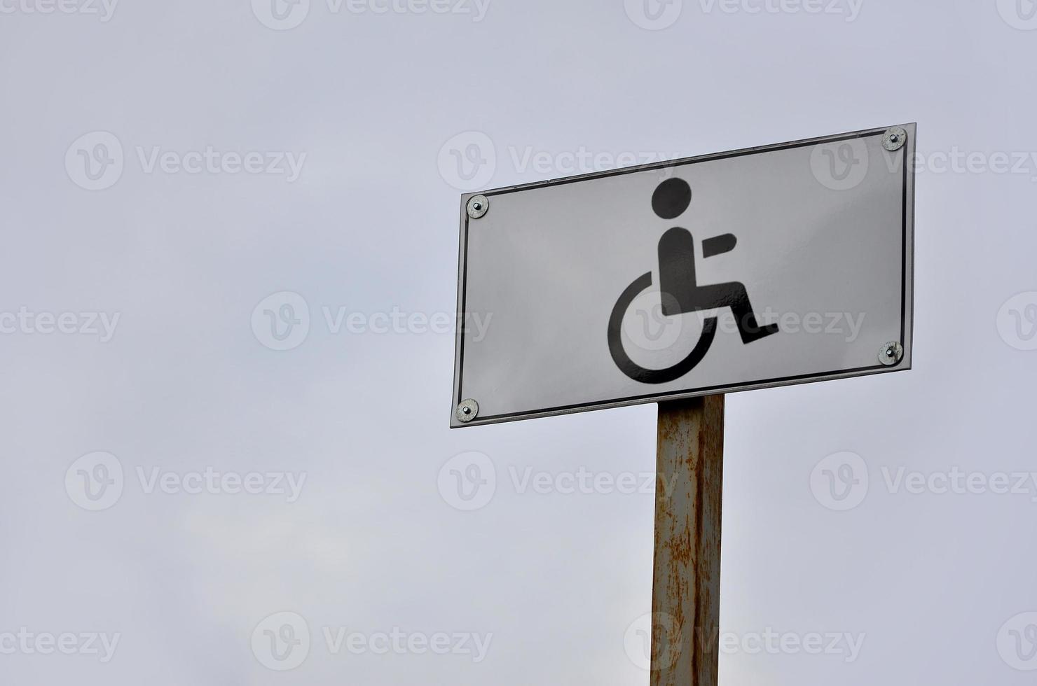 A road sign indicating the crossing of a road for disabled people. White road sign with a picture of a man sitting in a wheelchair photo