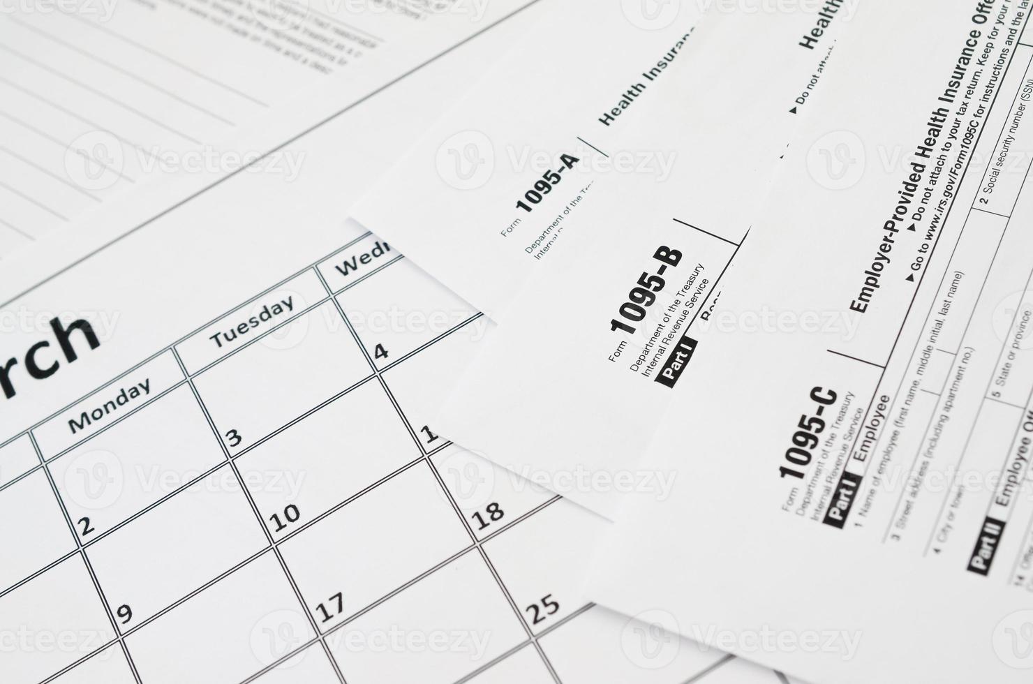 IRS Form 1095-A 1095-B and 1095-C blank lies on empty calendar page photo