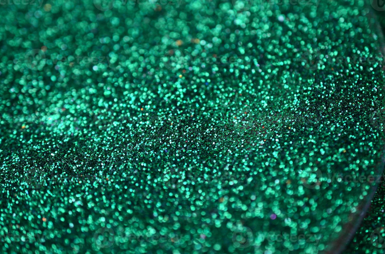 A huge amount of green decorative sequins. Background texture with shiny, small elements that reflect light in a random order. Glitter texture photo