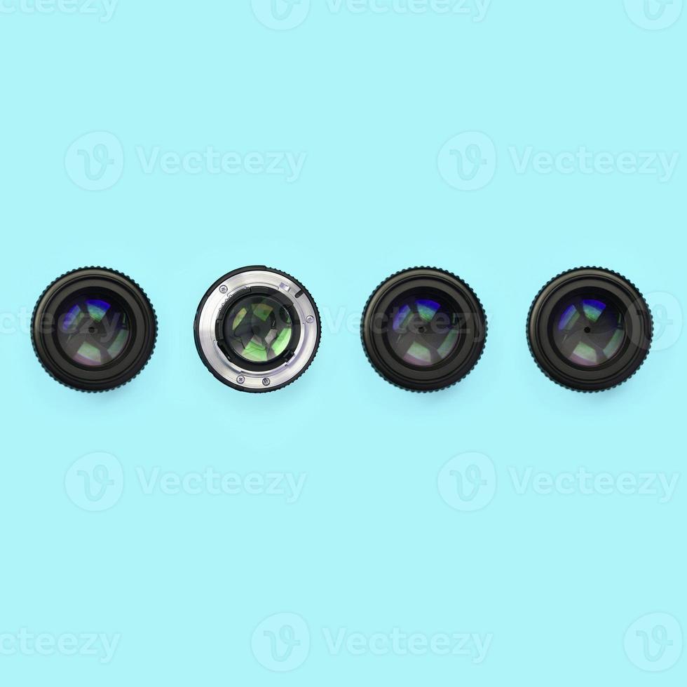 A few camera lenses with a closed aperture lie on texture background of fashion pastel blue color paper photo