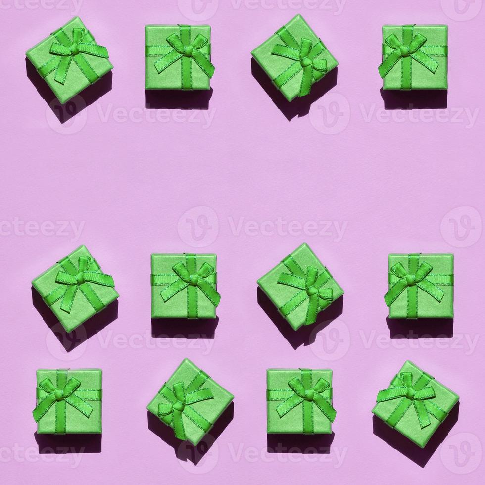 Many small green gift boxes on texture background of fashion trendy pastel pink color paper photo