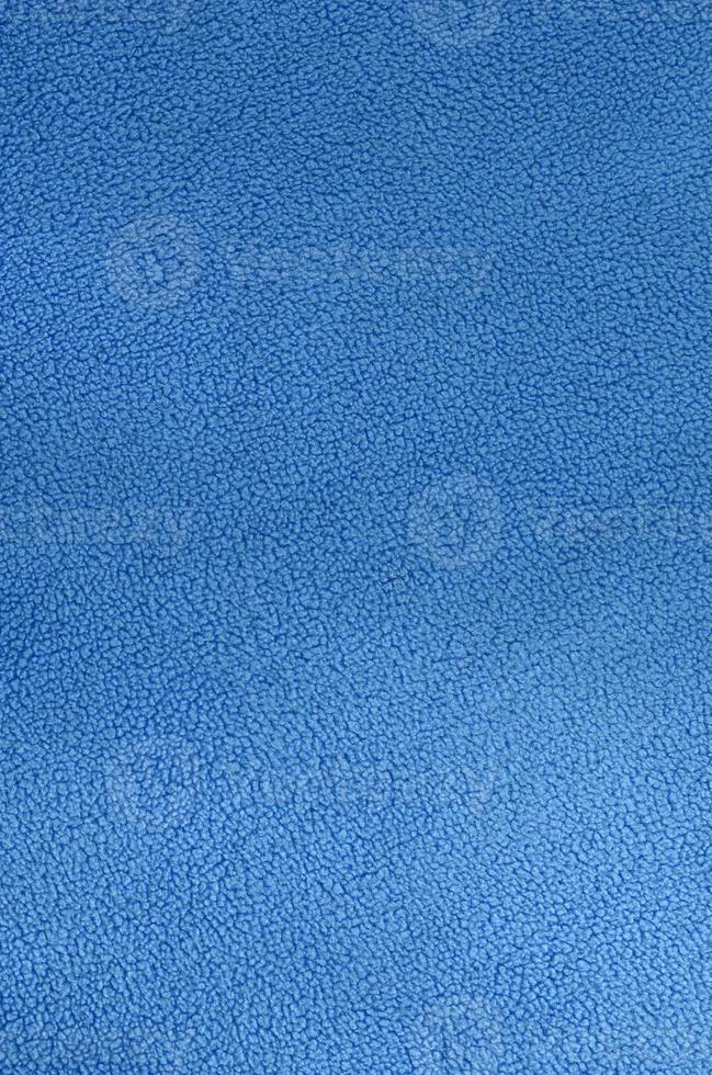 The blanket of furry blue fleece fabric. A background texture of light blue soft plush fleece material photo