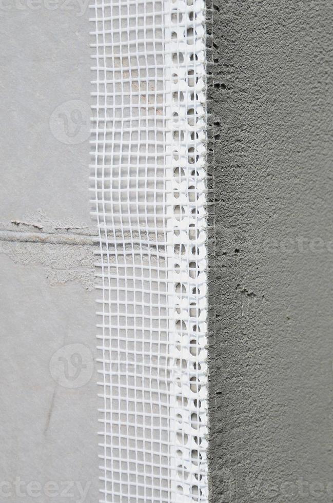 The texture of the wall, covered with gray polystyrene foam plates, which are coated with a reinforcing mixture with a plastic reinforcing profile corner. Stage of wall insulation photo