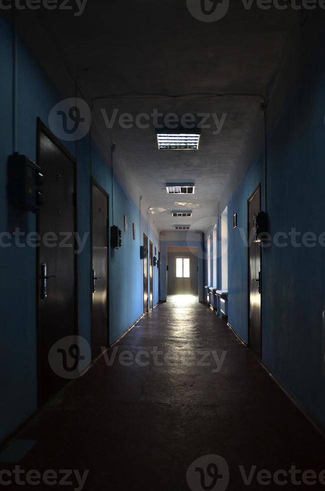 The gloomy corridor of a neglected public building. Public space in a poor residential high-rise building photo