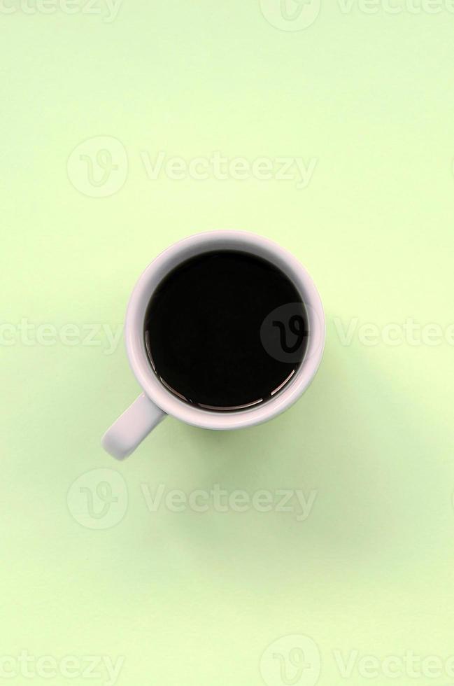Small white coffee cup on texture background of fashion pastel lime color paper photo