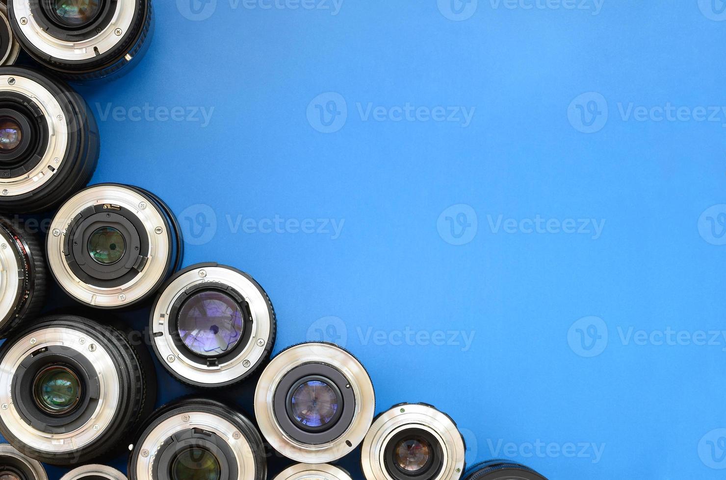 Several photographic lenses lie on a bright blue background. Space for text photo