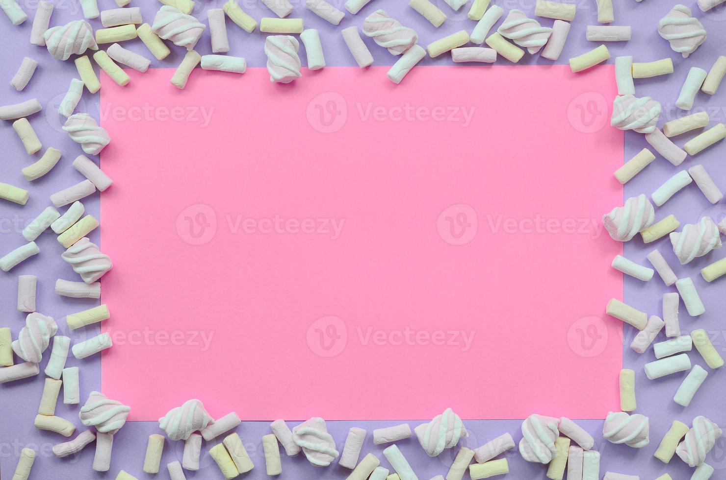 Colorful marshmallow laid out on violet and pink paper background. pastel creative textured framework. minimal photo