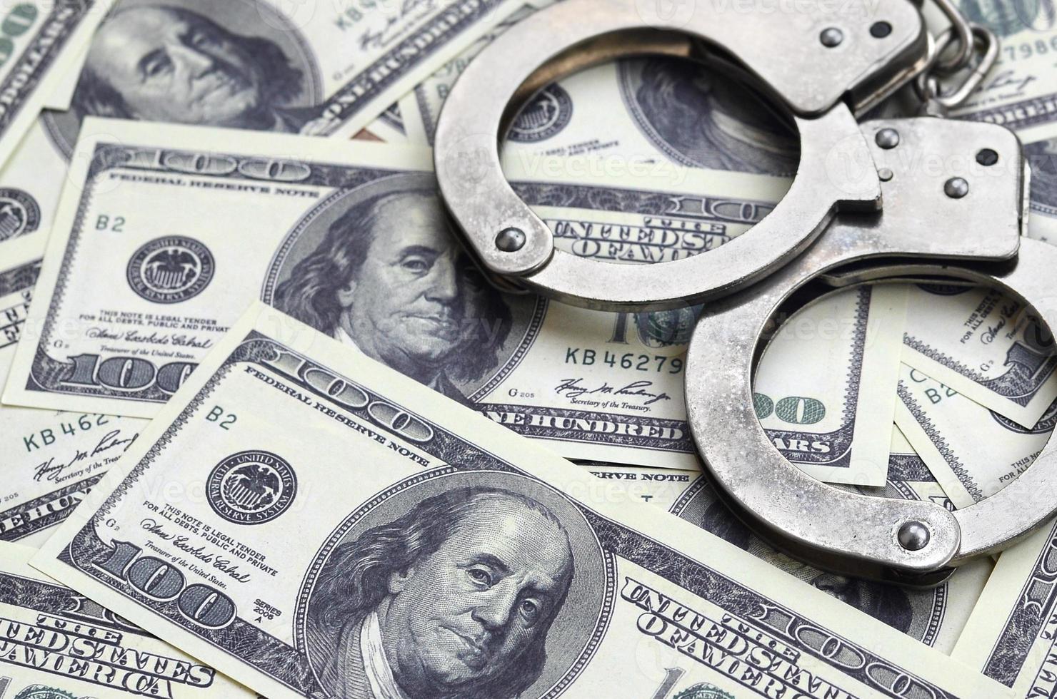 Police handcuffs lie on a lot of dollar bills. The concept of illegal possession of money, illegal transactions with US dollars. Economic Crime photo