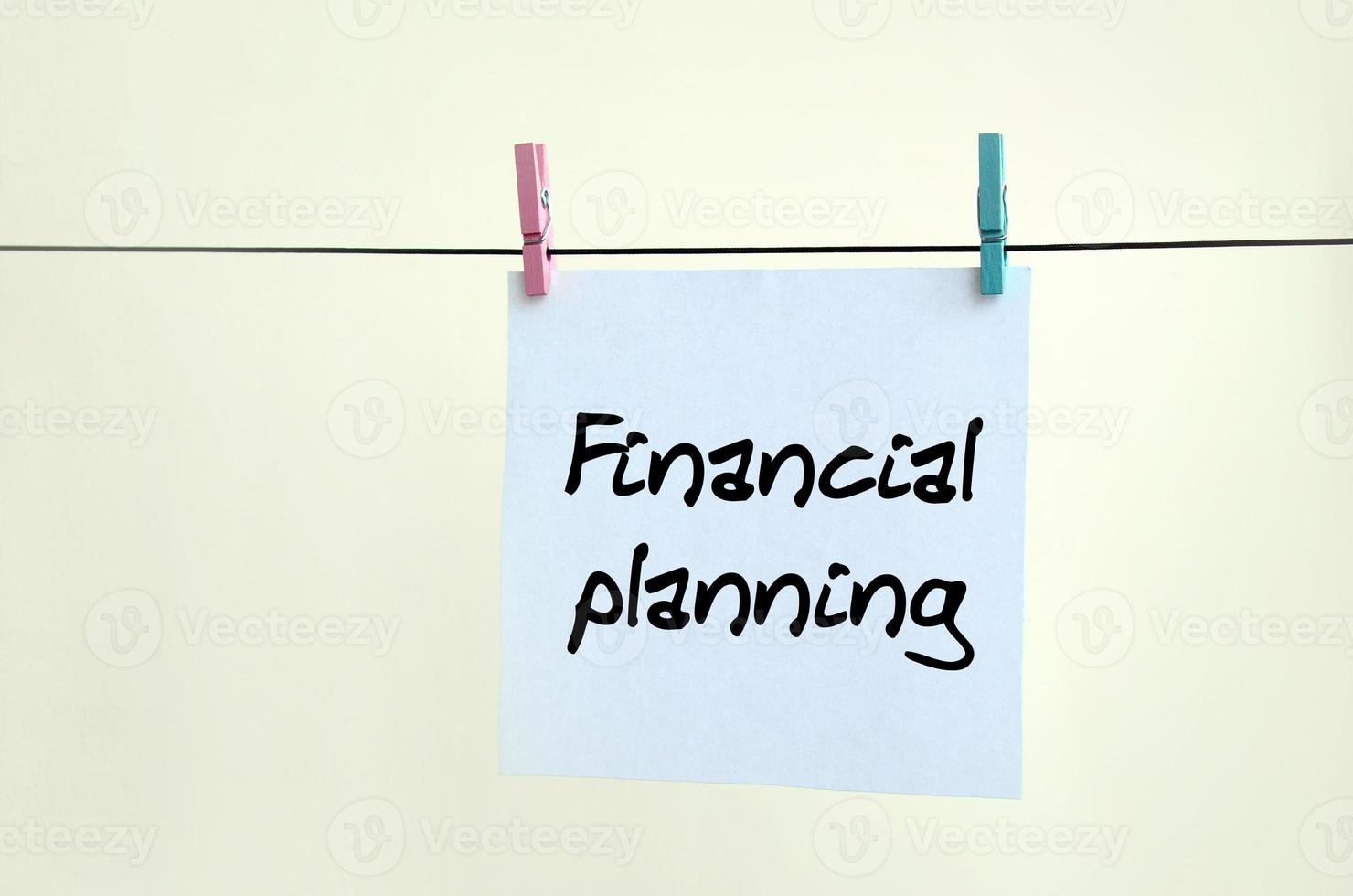 Financial Planning. Note is written on a white sticker that hangs with a clothespin on a rope on a background of beige wall photo