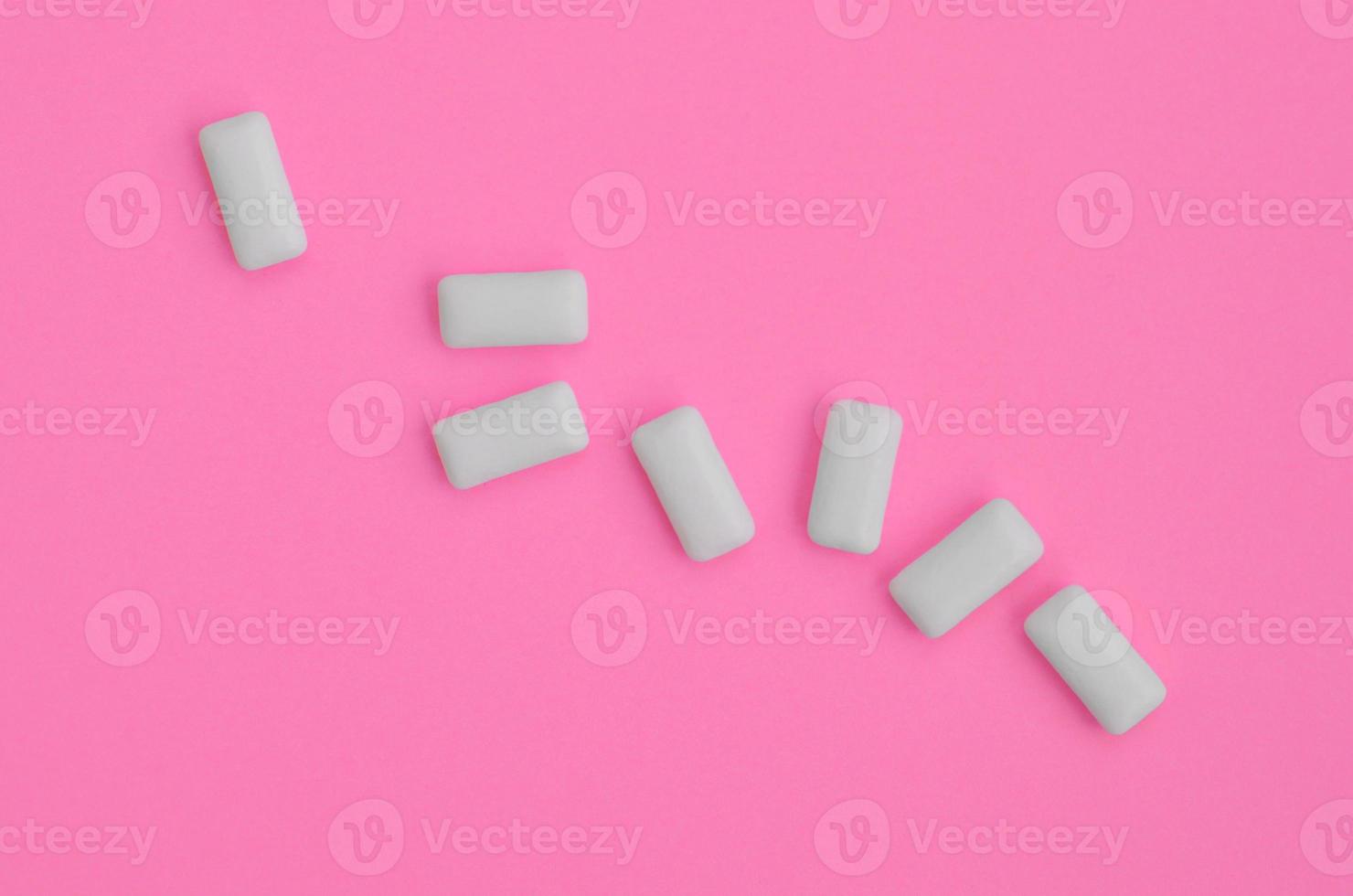 A few chewing gums lie on texture background of fashion pastel pink color paper in minimal concept photo