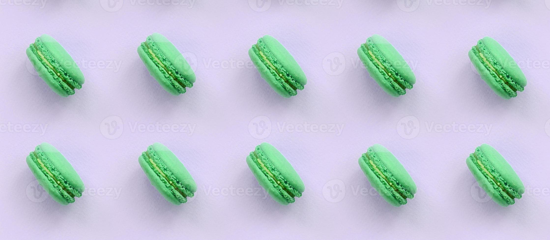 Green dessert cake macaron or macaroon on trendy pastel lilac background top view photo