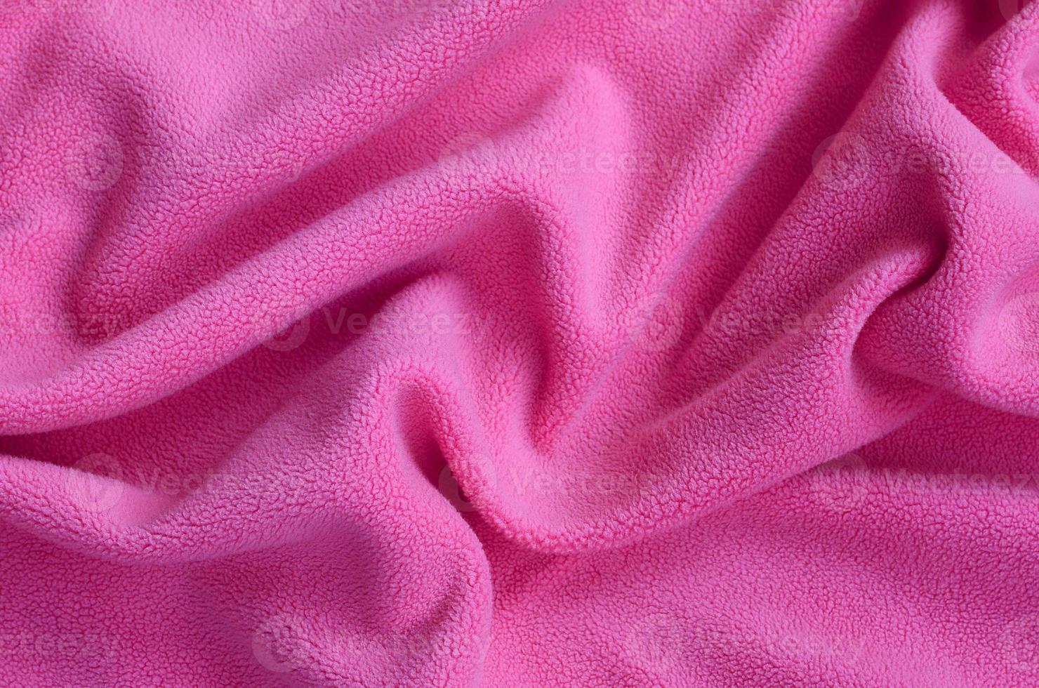 The blanket of furry pink fleece fabric. A background of light pink soft plush fleece material with a lot of relief folds photo