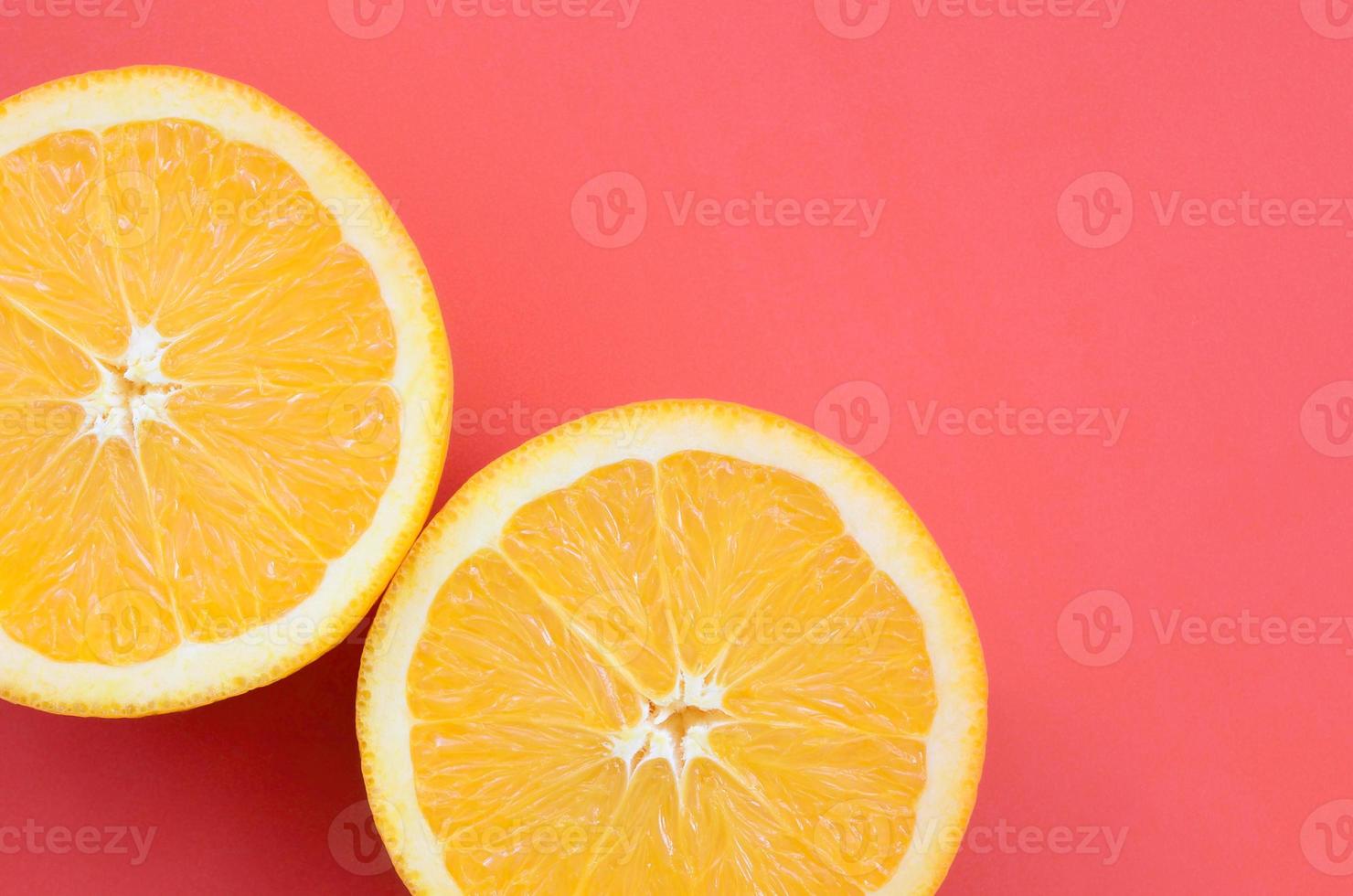 Top view of a several orange fruit slices on bright background in red color. A saturated citrus texture image photo