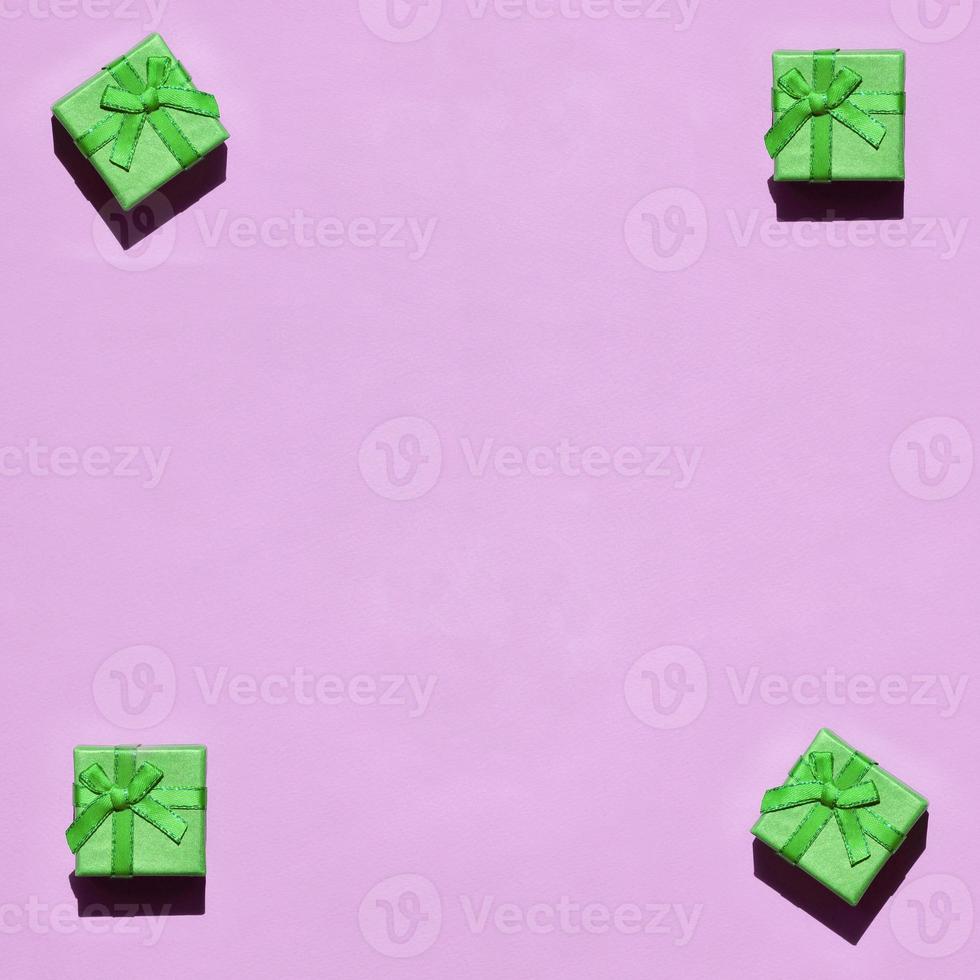 Many small green gift boxes on texture background of fashion trendy pastel pink color paper photo