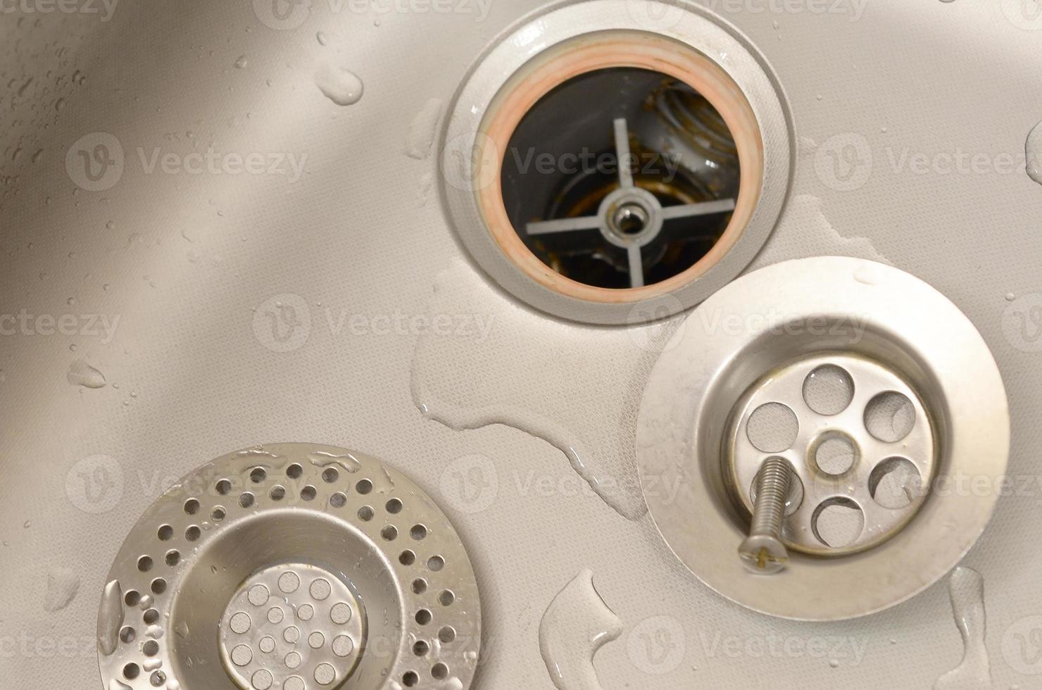 Silvery kitchen sink with a disassembled protective filter during the repair process photo