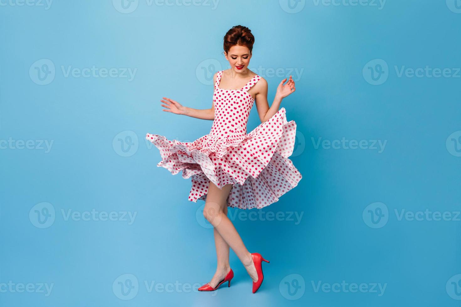vista completa de la mujer alegre bailando sobre fondo azul. pinup girl en  vestido de lunares divirtiéndose 12915293 Foto de stock en Vecteezy