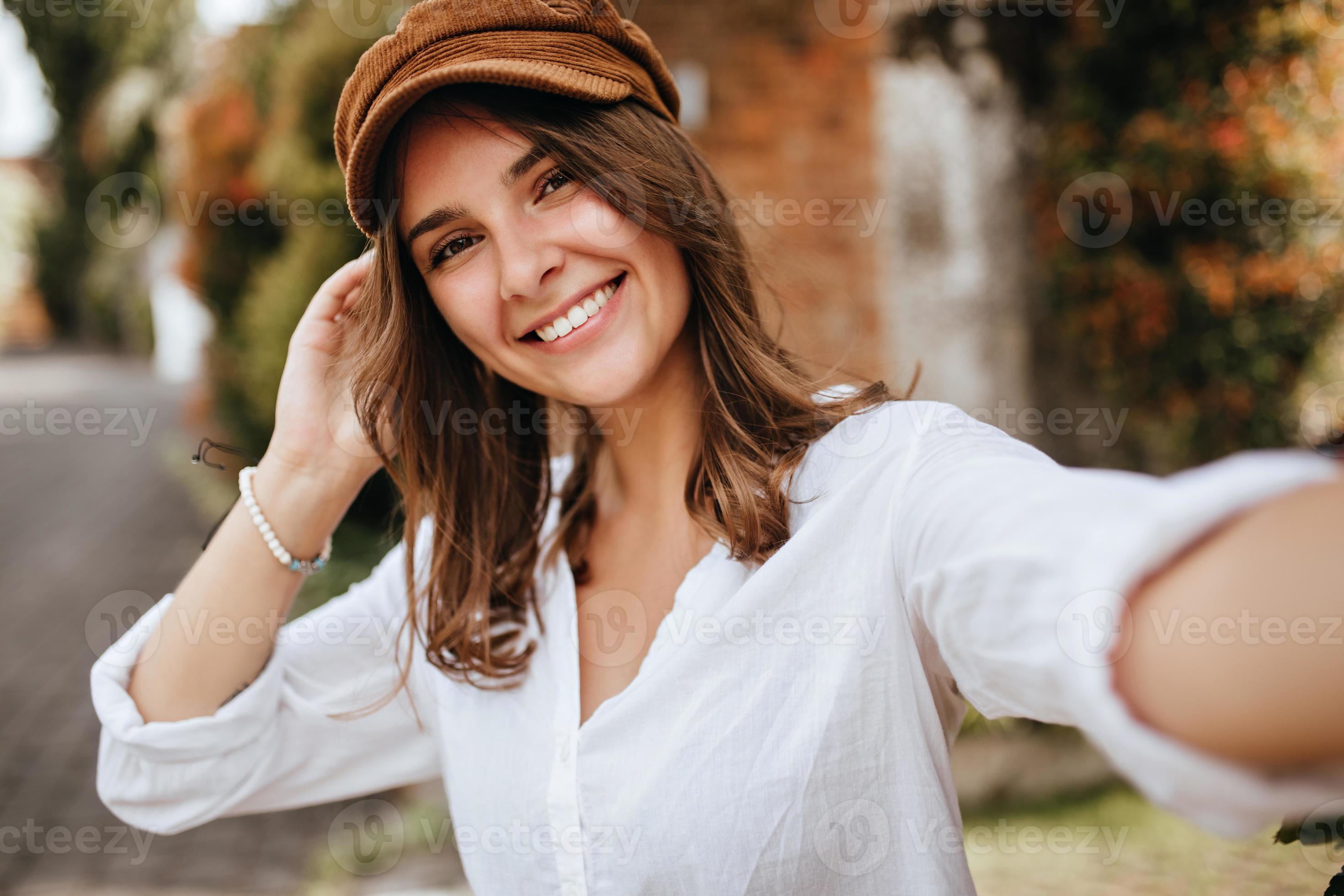 Young woman with short hair wearing white cotton blouse and brown hat. Girl  poses outdoors and take 12915537 Stock Photo at Vecteezy