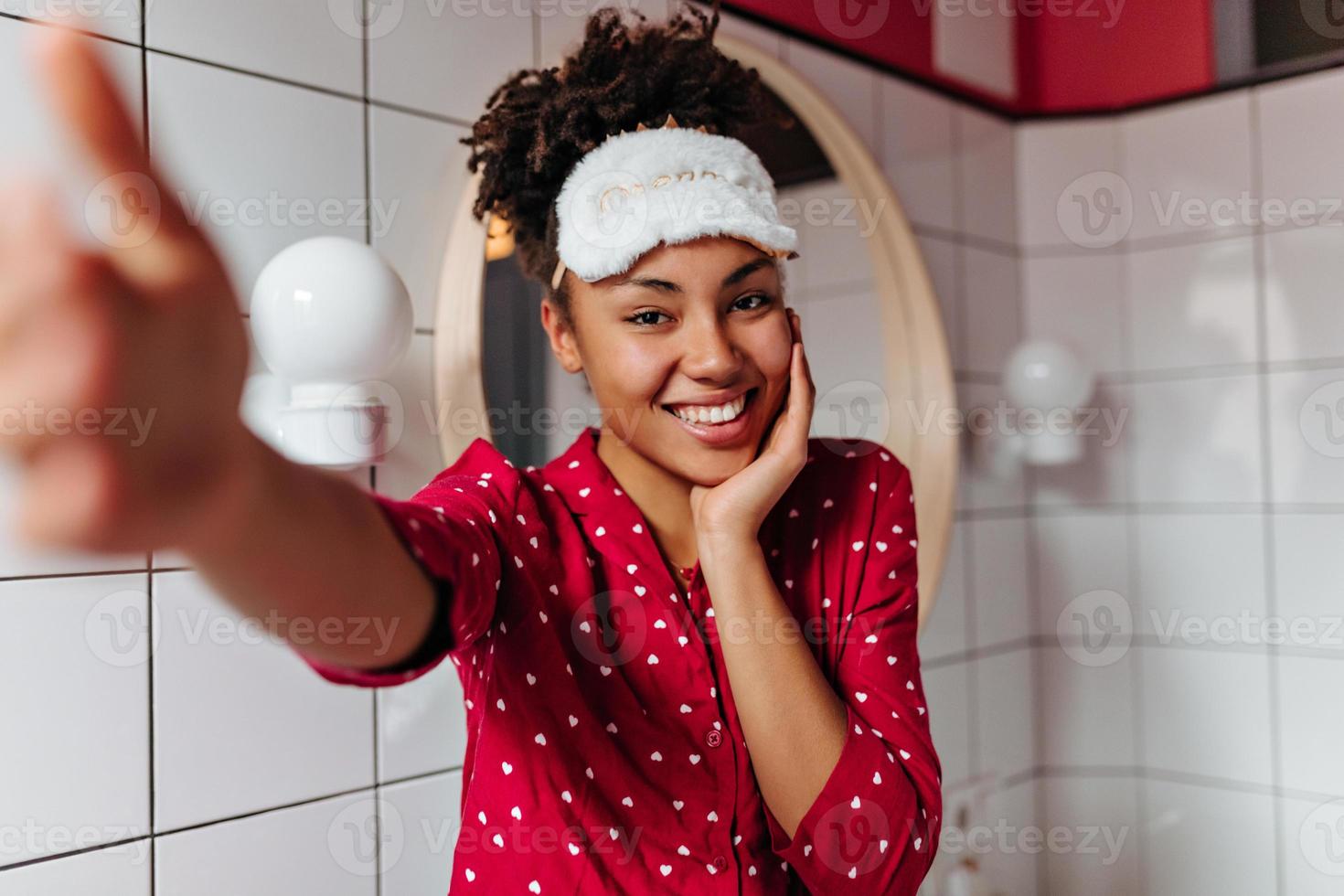 Beautiful girl in red polka dot pajamas with smile makes selfie in
