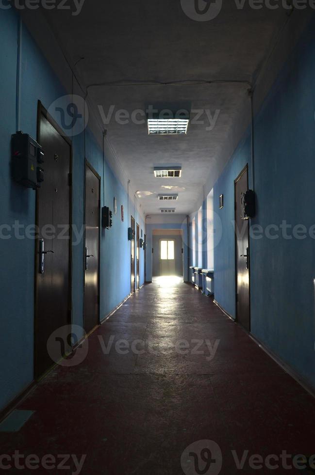 The gloomy corridor of a neglected public building. Public space in a poor residential high-rise building photo