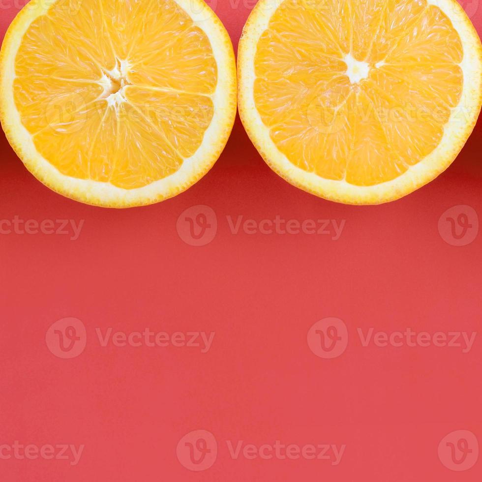 Top view of a several orange fruit slices on bright background in red color. A saturated citrus texture image photo