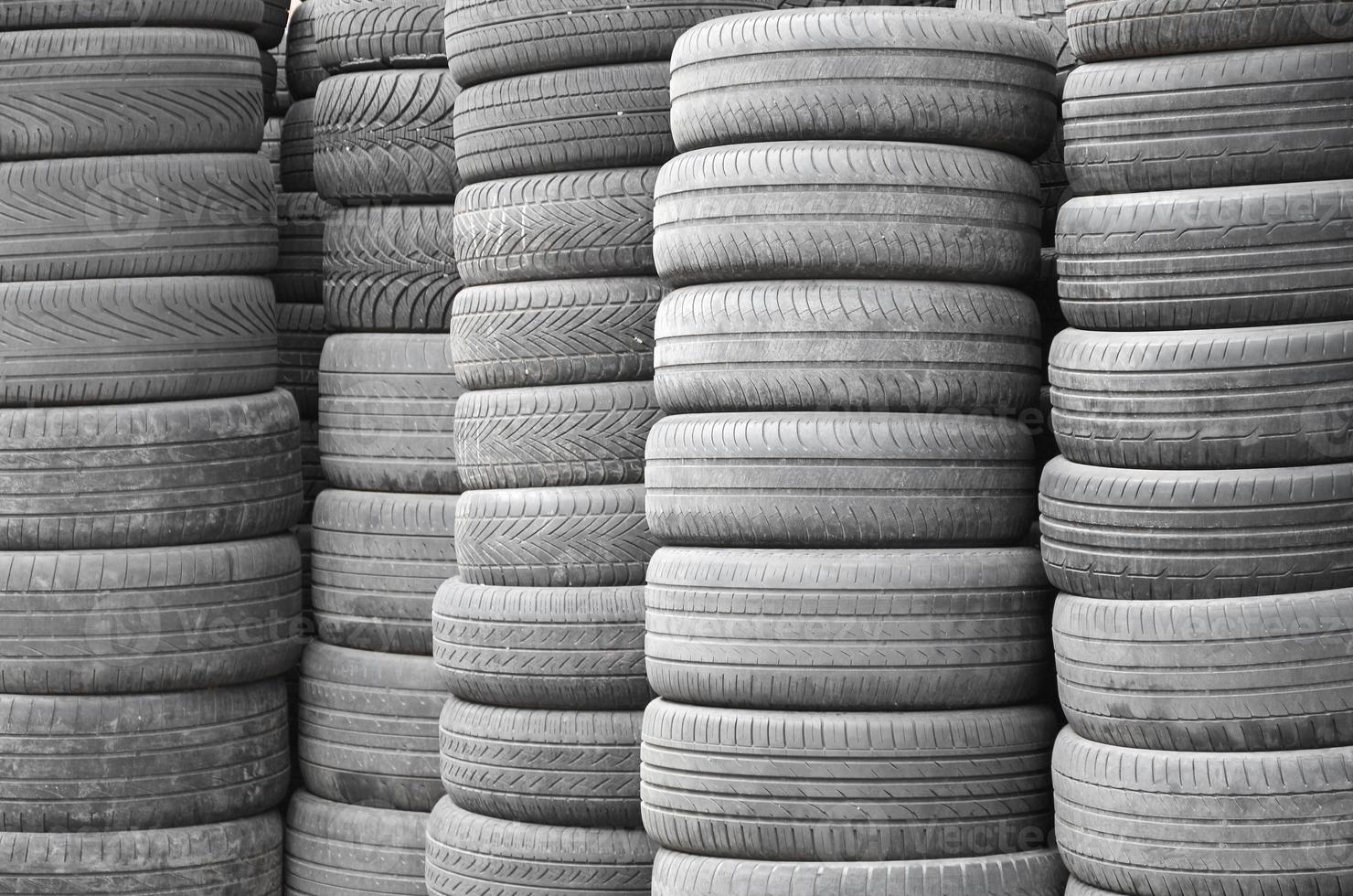 Old used tires stacked with high piles in secondary car parts shop garage photo