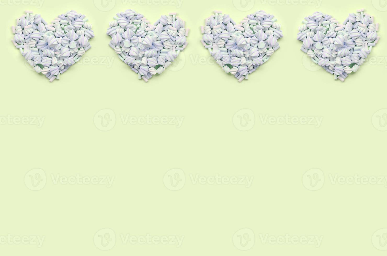 Colorful marshmallow laid out on lime and pink paper background. pastel creative textured hearts photo