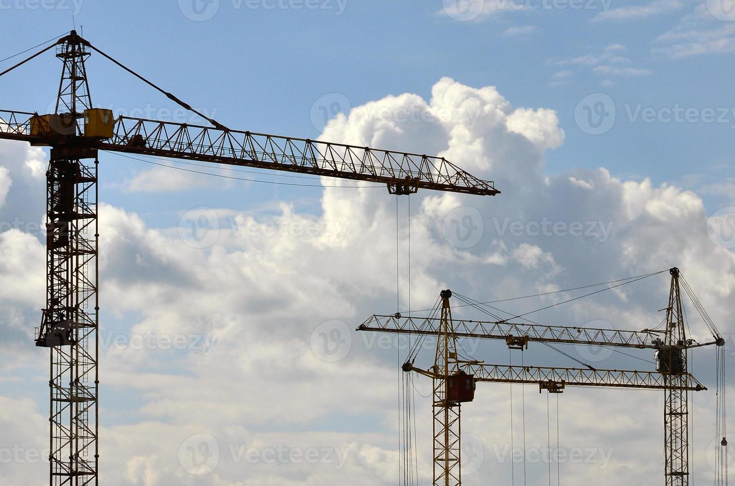 Tall and heavy construction crane towers against a blue sky photo