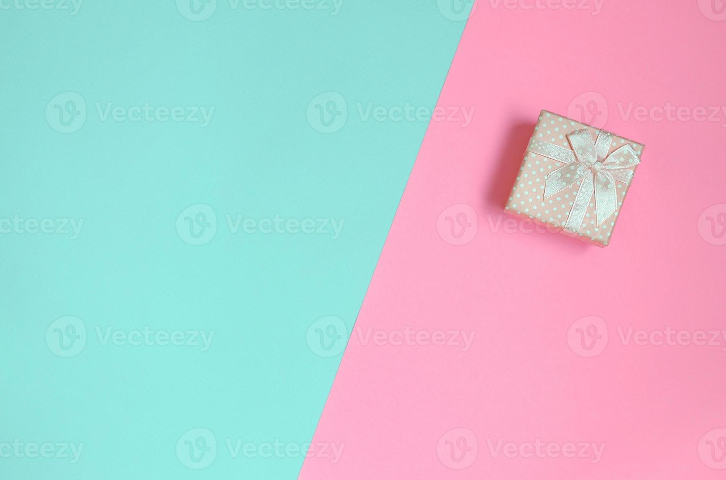 Small pink gift box lie on texture background of fashion pastel blue and pink colors paper in minimal concept photo