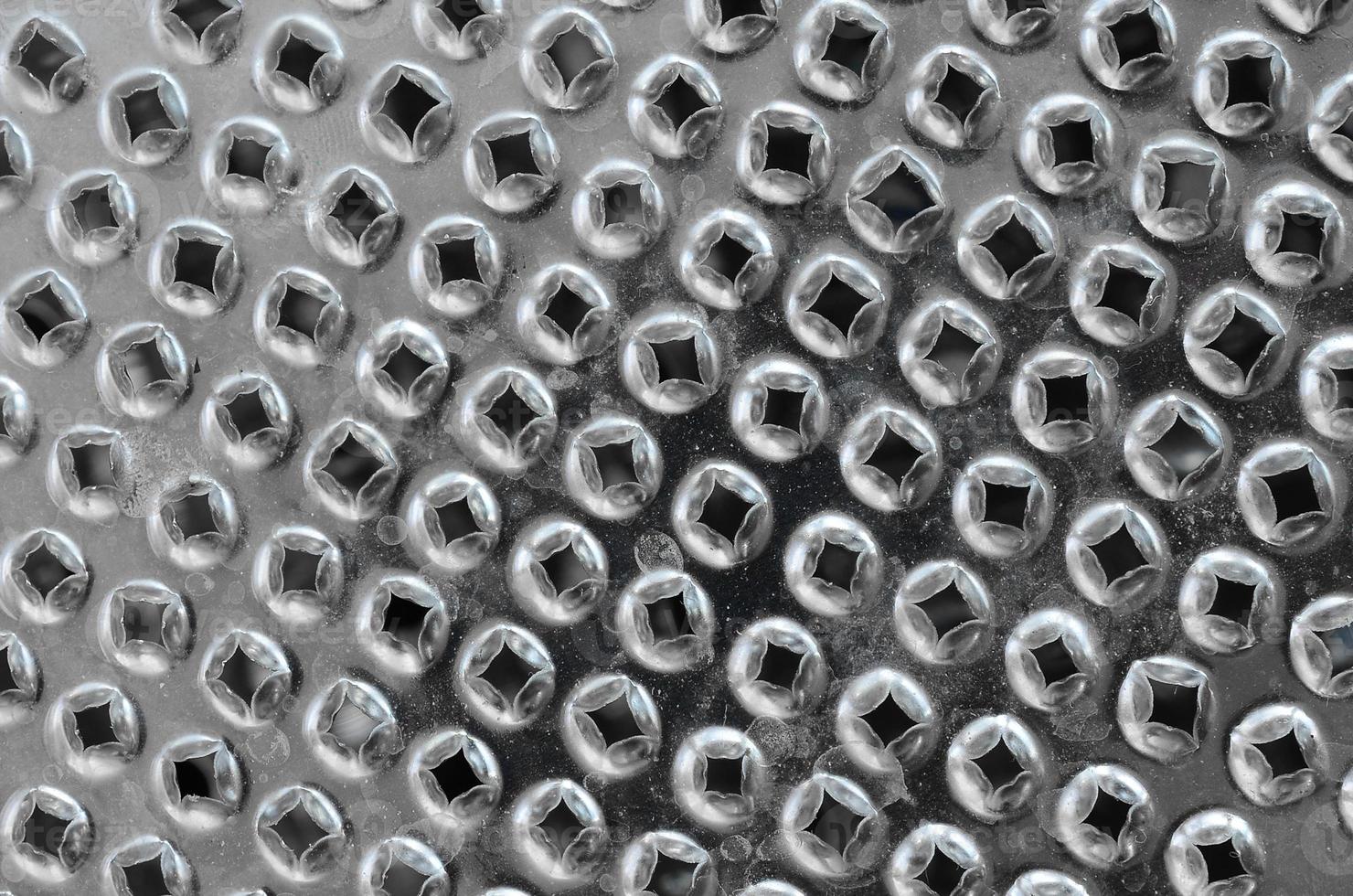 A fragment of a metal chrome grater close-up. Texture of blades for grinding food photo