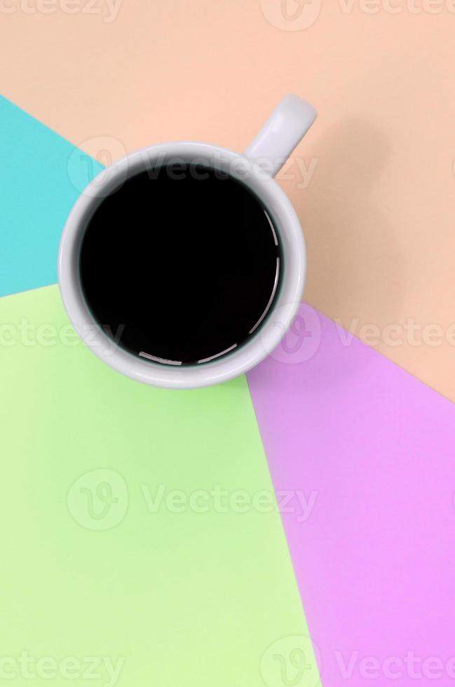 Small white coffee cup on texture background of fashion pastel pink, blue, coral and lime colors paper photo