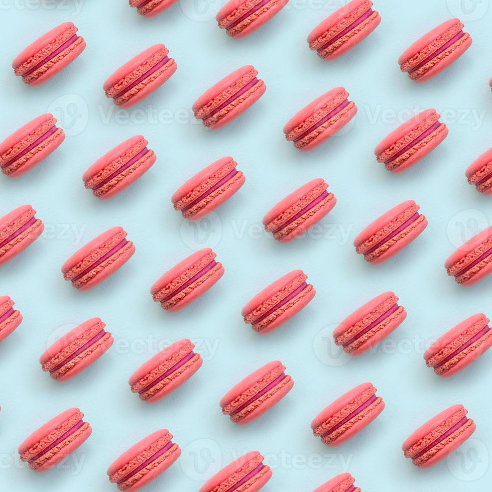 Pink dessert cake macaron or macaroon on trendy pastel blue background top view. Flat lay pattern composition photo