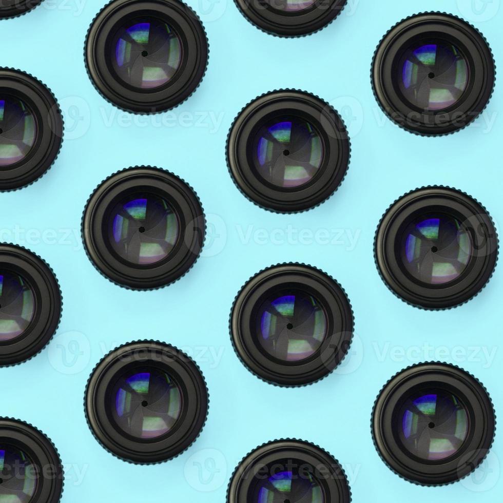 A few camera lenses with a closed aperture lie on texture background of fashion pastel blue color paper photo