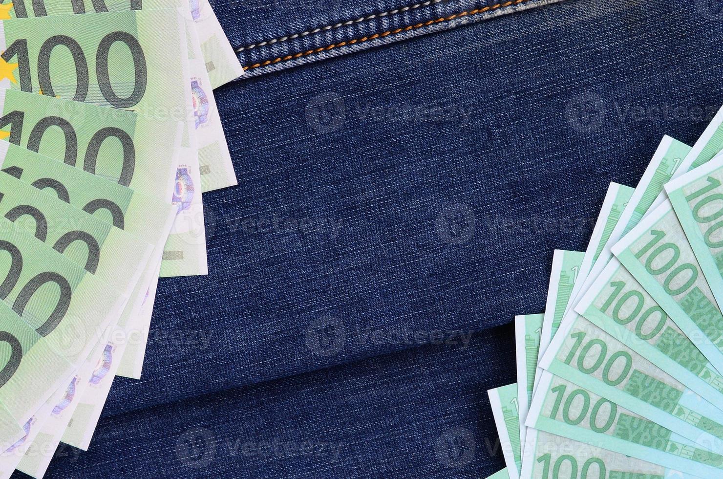 The fan of a lot of euro bills is on a dark denim surface. Background image photo