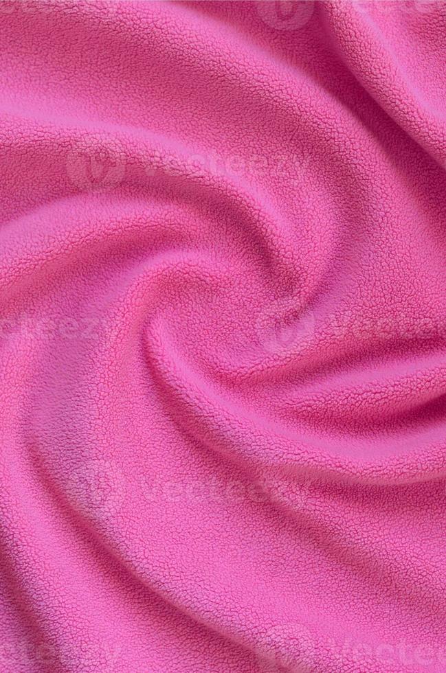 The blanket of furry pink fleece fabric. A background of light pink soft plush fleece material with a lot of relief folds photo