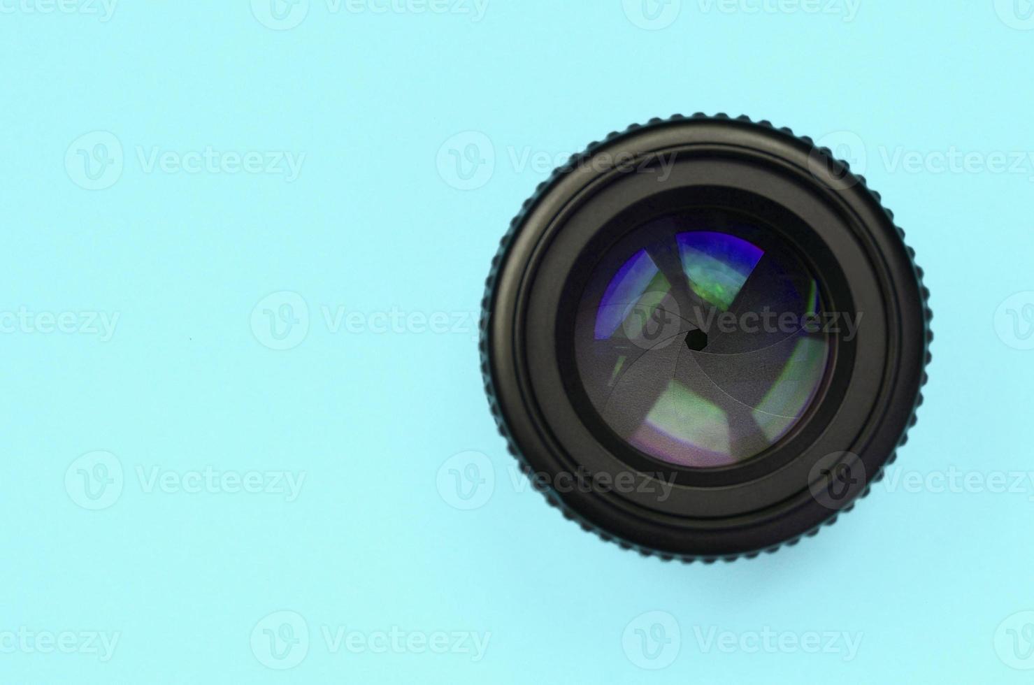 Camera lens with a closed aperture lie on texture background of fashion pastel blue color paper photo