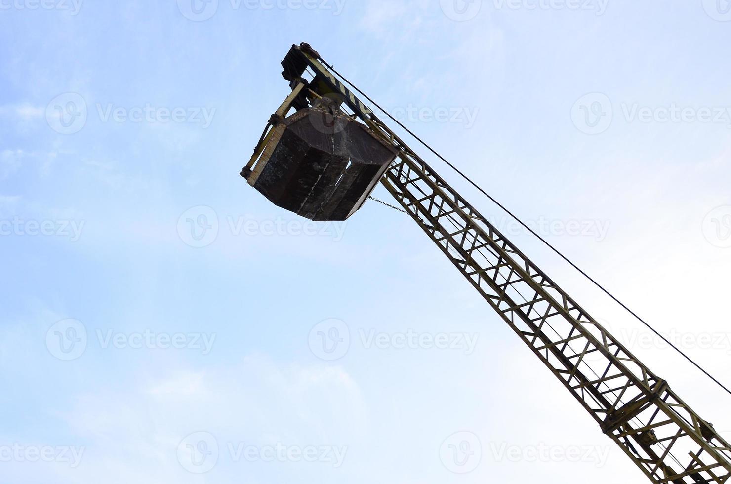 Old yellow mechanical clamshell grab on blue sky background photo