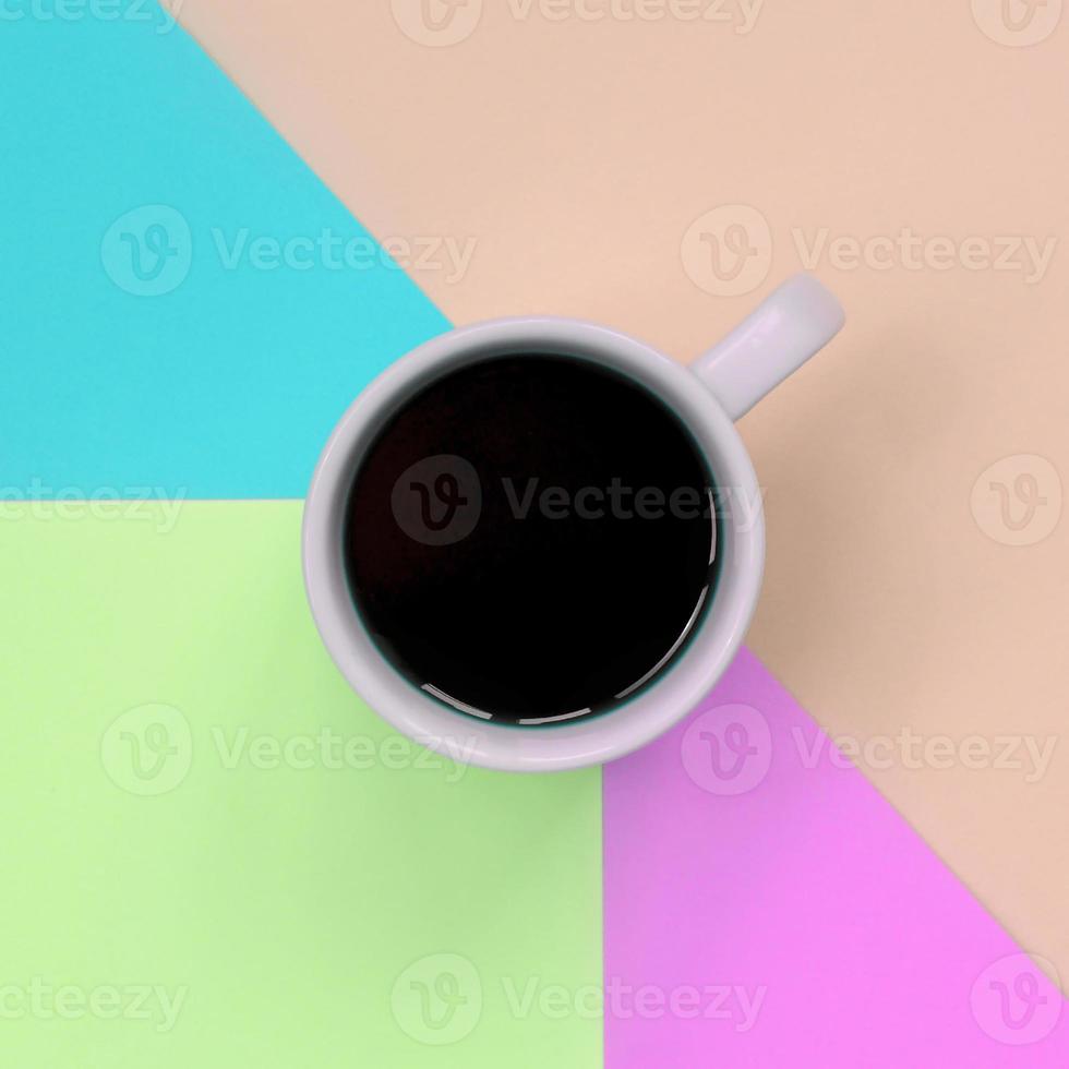 Small white coffee cup on texture background of fashion pastel pink, blue, coral and lime colors paper photo