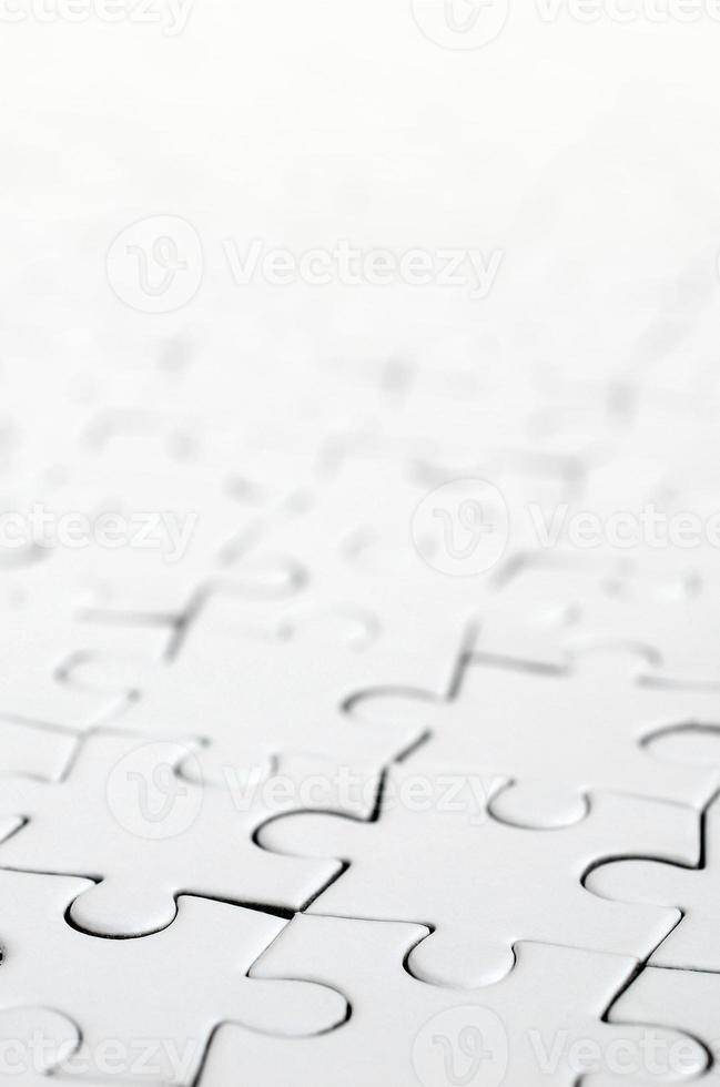 Close up of a white jigsaw puzzle in assembled state in perspective. Many components of a large whole mosaic are united photo