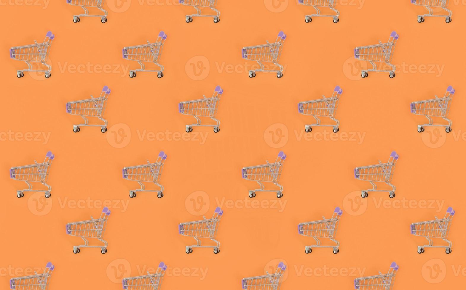 Shopping addiction, shopping lover or shopaholic concept. Many small empty shopping carts perform a pattern on a pastel colored paper background. Flat lay composition, top view photo