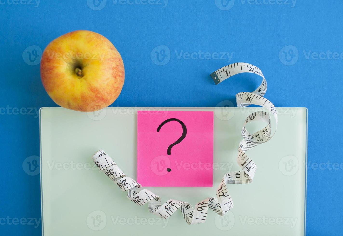 Electronic scales, a sticker with a question mark, an apple and a centimeter tape photo