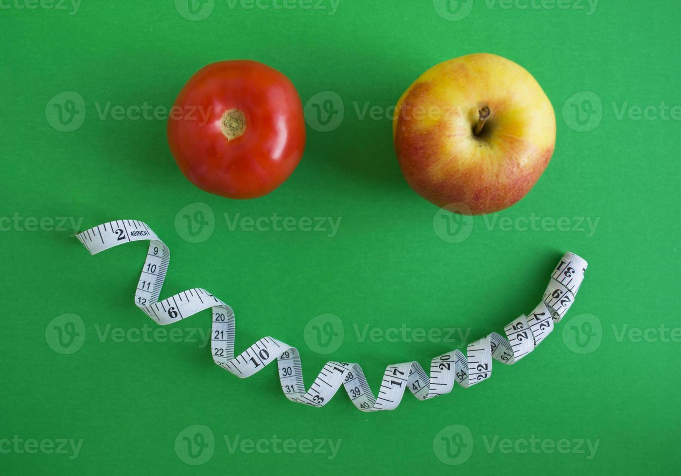 un tomate, una manzana y una cinta centimétrica foto