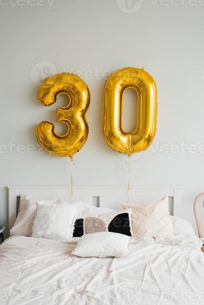 globos de helio para 30 años encima de la cama del cumpleañero o cumpleañera de la casa. mañana festiva foto